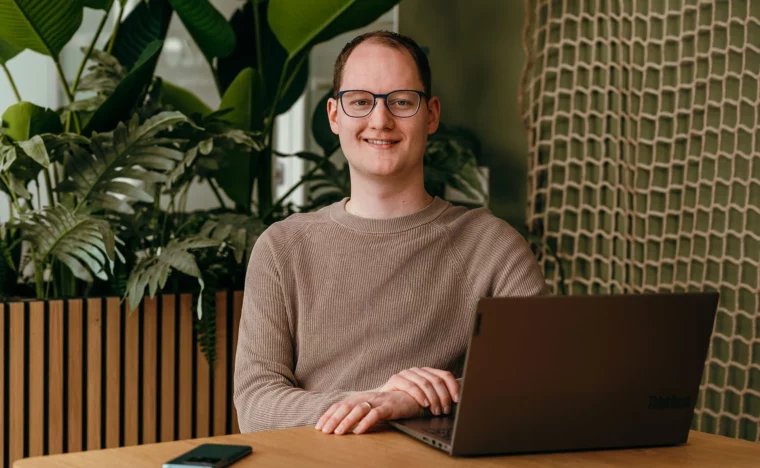 Een consultant legt uit hoe certificering werkt. Consultant zit aan tafel, achter een laptop.