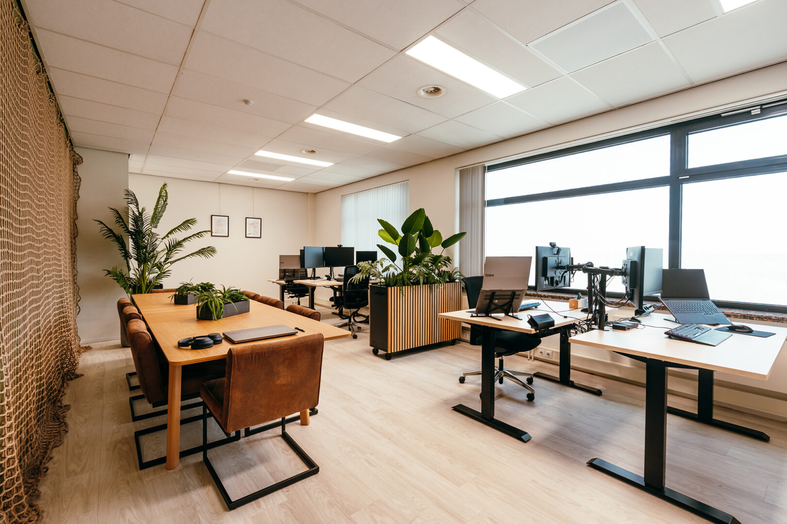 Foto van kantoor bij klein bedrijf met vier werkplekken en een eettafel.