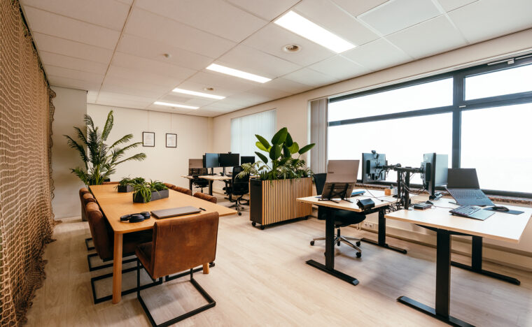 Foto van kantoor bij klein bedrijf met vier werkplekken en een eettafel.